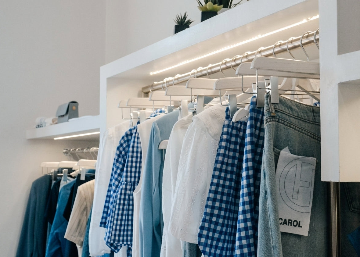 Interno della boutique Margé a Pomezia (Roma Sud), dettaglio dell'espositore con abbigliamento appeso in stile vintage tech e luci LED moderne, collezioni sempre aggiornate.